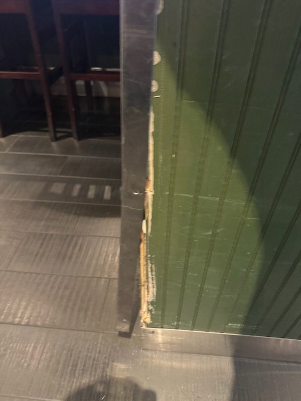 Green paneled wall with chipped exposed corner before the guard was installed