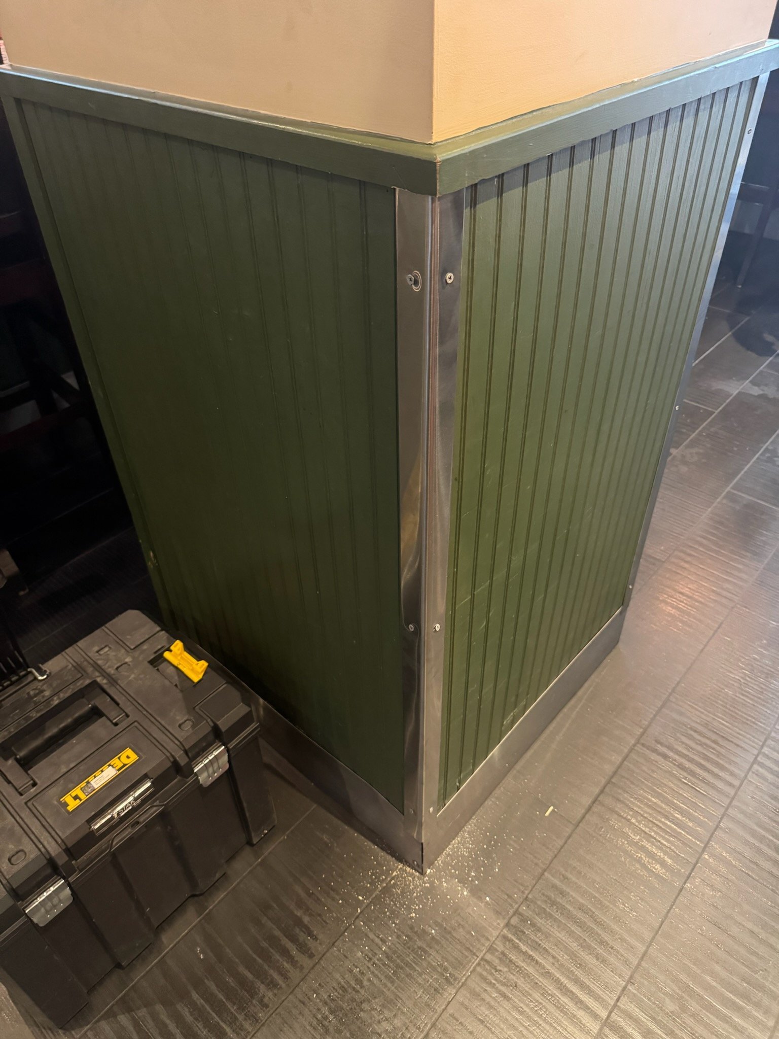 Metal corner guard installed on the green paneled wall